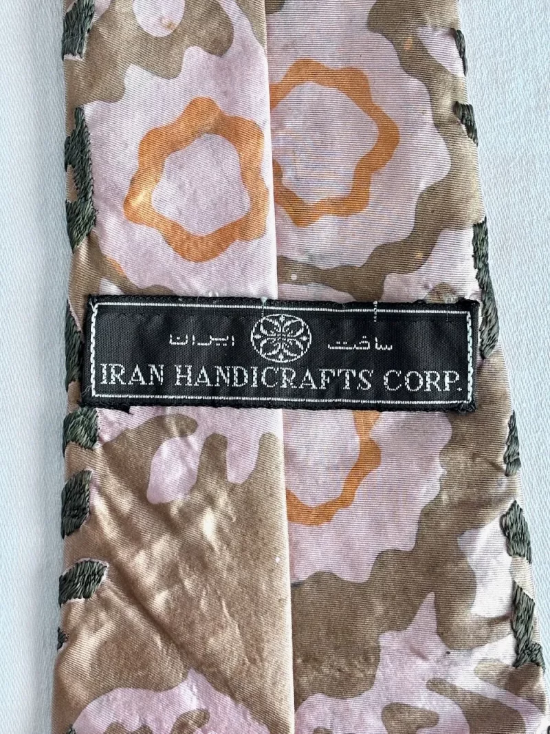 Close-up of camouflage fabric with a black label reading 'IRAN HANDICRAFTS CORP.'